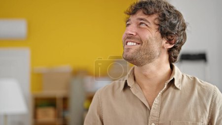 Foto de Joven hombre hispano sonriendo confiado mirando a un lado en un nuevo hogar - Imagen libre de derechos