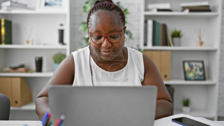 Foto de Trabajadora afroamericana enfocada sobresaliendo en los negocios. trabajando diligentemente en su computadora portátil, esta señora jefa encarna el éxito y el profesionalismo en su oficina. - Imagen libre de derechos