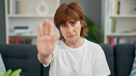 Photo for Middle age woman doing stop gesture with hand home - Royalty Free Image