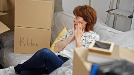 Foto de Mujer de mediana edad estresada sentada en un sofá en un nuevo hogar - Imagen libre de derechos