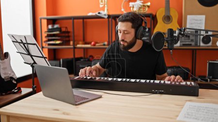 Téléchargez les photos : Jeune homme hispanique musicien ayant une leçon de piano en ligne au studio de musique - en image libre de droit