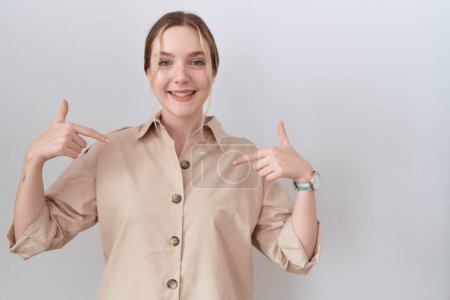 Foto de Mujer joven caucásica vistiendo camisa casual que mira confiada con sonrisa en la cara, señalándose con los dedos orgullosos y felices. - Imagen libre de derechos