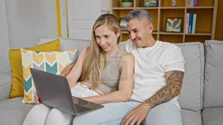 Foto de Hombre y mujer pareja usando portátil sentado en el sofá en casa - Imagen libre de derechos
