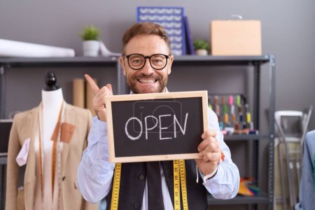 Photo for Middle age man with beard dressmaker designer holding open sign smiling happy pointing with hand and finger to the side - Royalty Free Image