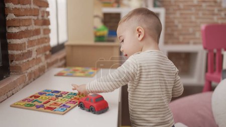 Foto de Adorable niño jugando con el juego de matemáticas en la mesa en el jardín de infantes - Imagen libre de derechos