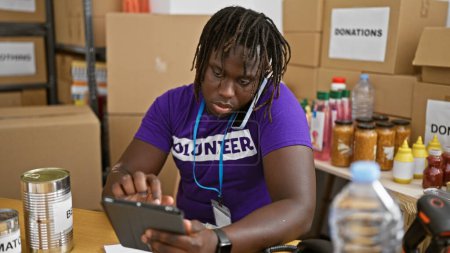 Foto de Hombre afroamericano voluntario hablando por teléfono usando touchpad en el centro de caridad - Imagen libre de derechos