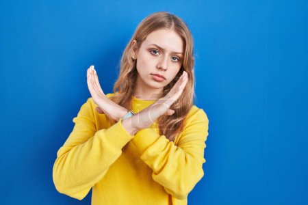 Téléchargez les photos : Jeune femme caucasienne debout sur fond bleu expression de rejet croisant les bras faisant signe négatif, visage en colère - en image libre de droit