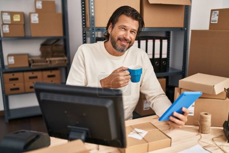 Photo for Middle age man ecommerce business worker using touchpad drinking coffee at office - Royalty Free Image
