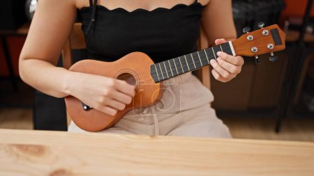 Téléchargez les photos : Jeune belle musicienne hispanique jouant de l'ukulélé au studio de musique - en image libre de droit