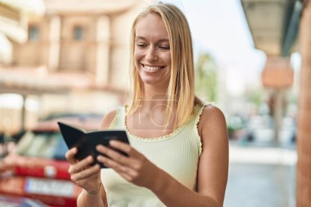 Téléchargez les photos : Jeune femme blonde souriante confiante lecture canada passeport à la rue - en image libre de droit
