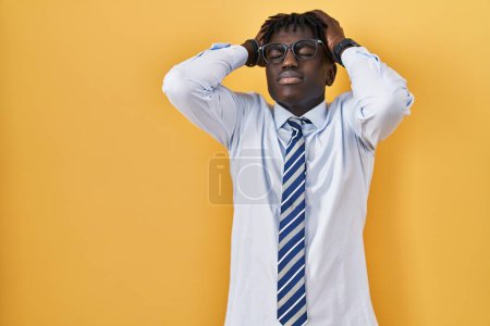 Téléchargez les photos : Homme africain avec dreadlocks debout sur fond jaune souffrant de maux de tête désespérés et stressés parce que la douleur et la migraine. mains sur la tête. - en image libre de droit
