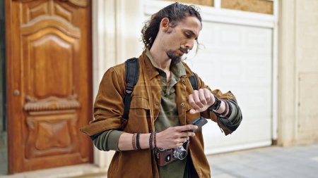 Téléchargez les photos : Jeune homme hispanique touriste en utilisant smartphone regarder la rue - en image libre de droit