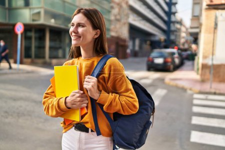 Photo for Young blonde woman student wearing backpack holding books at street - Royalty Free Image