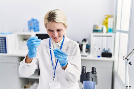 Photo for Young blonde woman scientist pouring liquid on sample at laboratory - Royalty Free Image