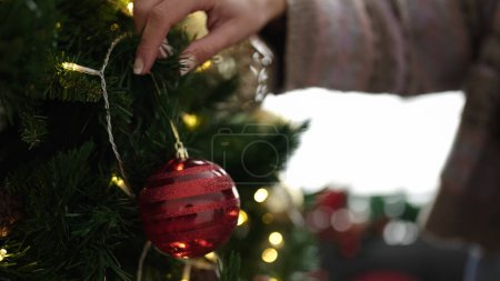 Photo for Young blonde woman decorating christmas tree at home - Royalty Free Image