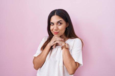 Photo for Young arab woman standing over pink background laughing nervous and excited with hands on chin looking to the side - Royalty Free Image