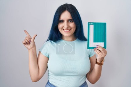 Photo for Young modern girl with blue hair holding l sign for new driver smiling happy pointing with hand and finger to the side - Royalty Free Image
