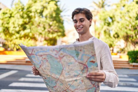 Photo for Young caucasian man smiling confident holding city map at park - Royalty Free Image