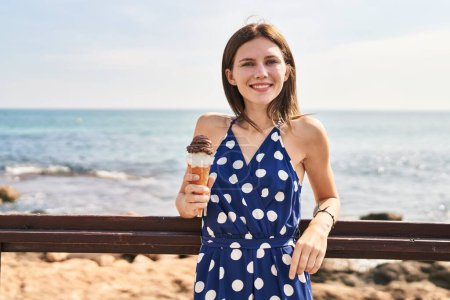 Photo for Young blonde woman tourist smiling confident holding ice cream at seaside - Royalty Free Image
