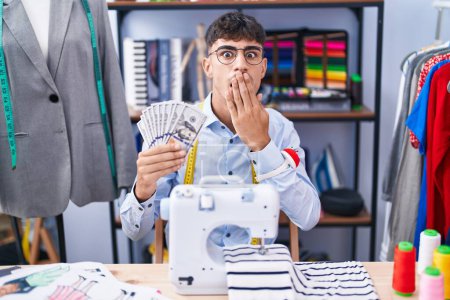 Photo for Young hispanic man dressmaker designer holding dollars covering mouth with hand, shocked and afraid for mistake. surprised expression - Royalty Free Image