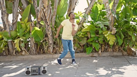 Téléchargez les photos : Homme afro-américain souriant danse confiante au parc - en image libre de droit