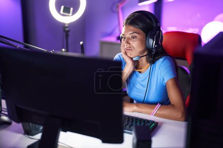 Foto de Morena joven jugando a videojuegos pensando que parece cansado y aburrido con problemas de depresión con los brazos cruzados. - Imagen libre de derechos