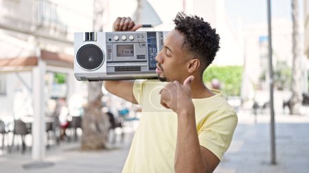 Photo for African american man holding boombox doing thumb up gesture at street - Royalty Free Image