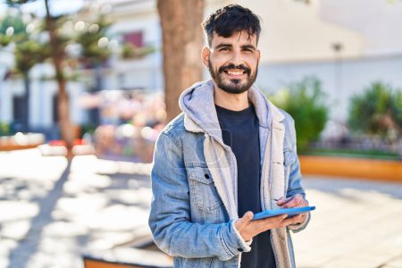 Photo for Young hispanic man smiling confident using touchpad at park - Royalty Free Image