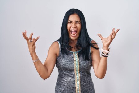 Photo for Mature hispanic woman standing over white background crazy and mad shouting and yelling with aggressive expression and arms raised. frustration concept. - Royalty Free Image