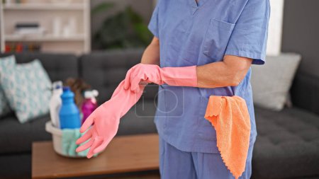 Téléchargez les photos : Femme d'âge moyen nettoyant professionnel portant des gants à la maison - en image libre de droit