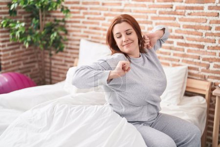 Photo for Young beautiful plus size woman waking up stretching arms at bedroom - Royalty Free Image