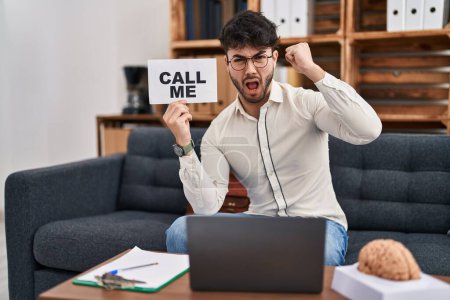 Photo for Hispanic man with beard working at therapy office holding call me sign annoyed and frustrated shouting with anger, yelling crazy with anger and hand raised - Royalty Free Image