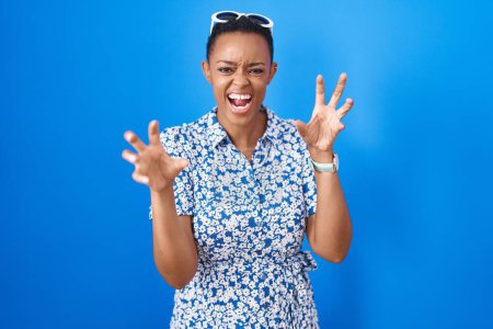 Photo for African american woman standing over blue background smiling funny doing claw gesture as cat, aggressive and sexy expression - Royalty Free Image