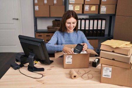 Photo for Young blonde woman ecommerce business worker packing data phone on cardboard box at office - Royalty Free Image