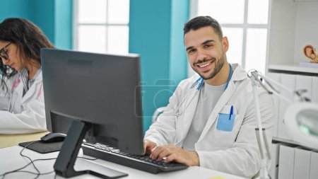 Téléchargez les photos : Médecins hommes et femmes utilisant l'ordinateur prenant des notes souriantes à la clinique - en image libre de droit