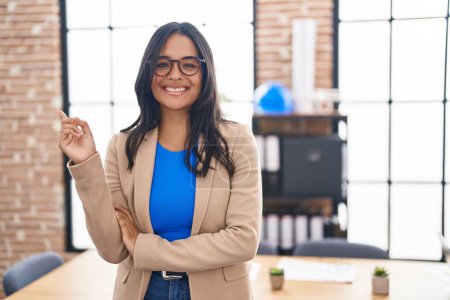 Photo for Brunette woman working at the office wearing glasses smiling happy pointing with hand and finger to the side - Royalty Free Image