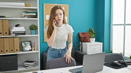 Téléchargez les photos : Jeune femme blonde travailleuse d'affaires parlant sur smartphone travaillant au bureau - en image libre de droit