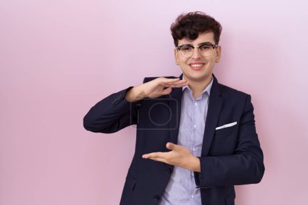 Photo for Young non binary man with beard wearing suit and tie gesturing with hands showing big and large size sign, measure symbol. smiling looking at the camera. measuring concept. - Royalty Free Image