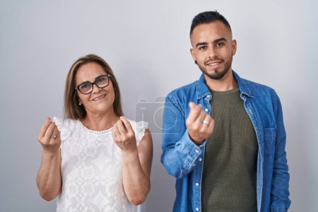 Téléchargez les photos : Mère hispanique et fils debout ensemble faisant geste d'argent avec les mains, demandant le paiement du salaire, entreprise millionnaire - en image libre de droit