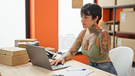 Téléchargez les photos : Femme hispanique avec amputé bras ecommerce travailleur d'affaires en utilisant un ordinateur portable avec un visage sérieux au bureau - en image libre de droit