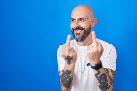 Téléchargez les photos : Hispanic man with tattoos standing over blue background showing middle finger doing fuck you bad expression, provocation and rude attitude. screaming excited - en image libre de droit