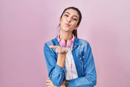 Photo for Young beautiful woman standing over pink background looking at the camera blowing a kiss with hand on air being lovely and sexy. love expression. - Royalty Free Image