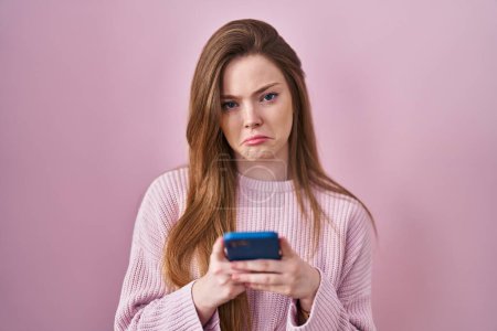 Foto de Young caucasian woman using smartphone typing message depressed and worry for distress, crying angry and afraid. sad expression. - Imagen libre de derechos