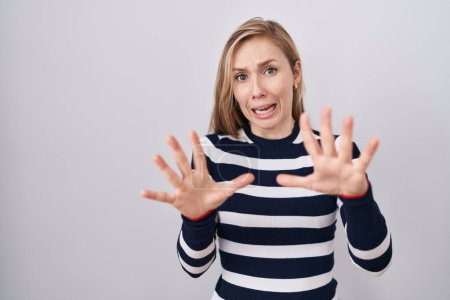 Photo for Young caucasian woman wearing casual navy sweater afraid and terrified with fear expression stop gesture with hands, shouting in shock. panic concept. - Royalty Free Image