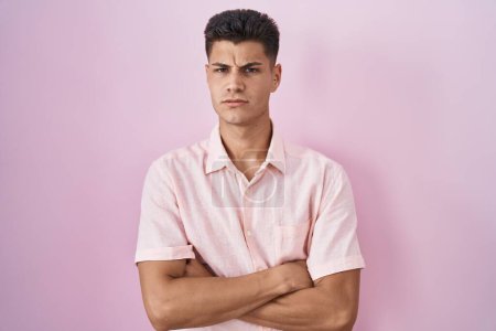 Téléchargez les photos : Young hispanic man standing over pink background skeptic and nervous, disapproving expression on face with crossed arms. negative person. - en image libre de droit