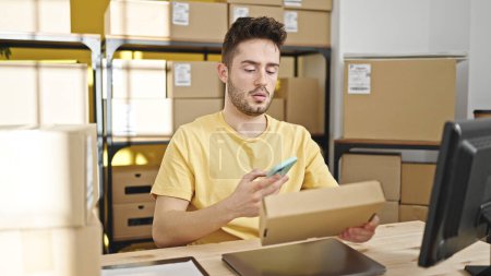 Foto de Hombre hispano joven comercio electrónico trabajador de negocios escaneando paquetes en la oficina - Imagen libre de derechos