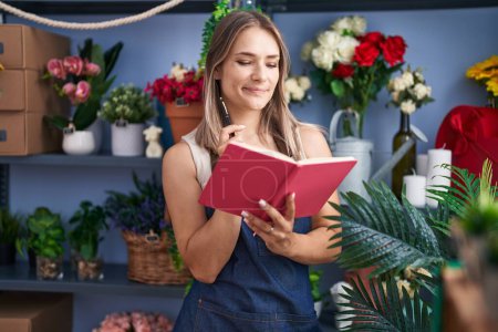 Photo for Young caucasian woman florist reading notebook at florist - Royalty Free Image
