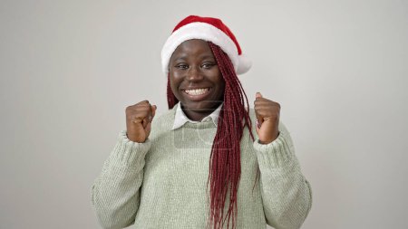 Téléchargez les photos : Femme africaine aux cheveux tressés célébrant le port du chapeau de Noël sur fond blanc - en image libre de droit