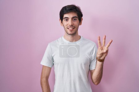 Photo for Young hispanic man standing over pink background showing and pointing up with fingers number three while smiling confident and happy. - Royalty Free Image