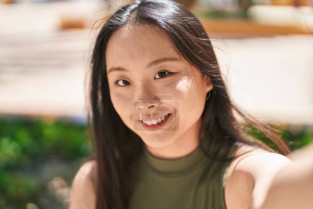 Téléchargez les photos : Young chinese woman smiling confident making selfie by camera at park - en image libre de droit